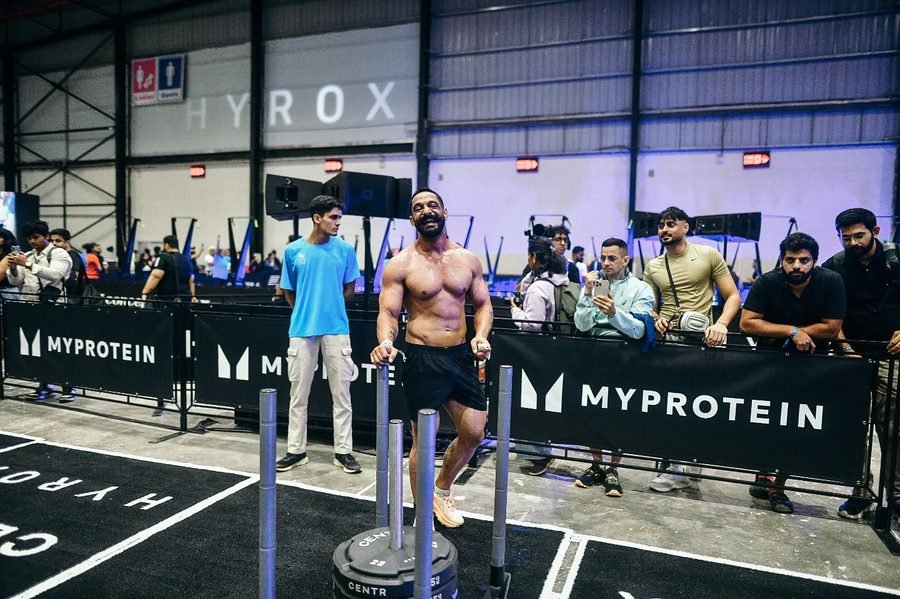 Satnaam driving a weighted sled down the floor at HYROX