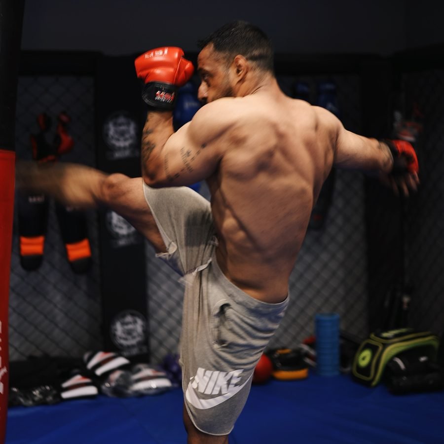 Satnaam throwing a head kick in a boxing gym