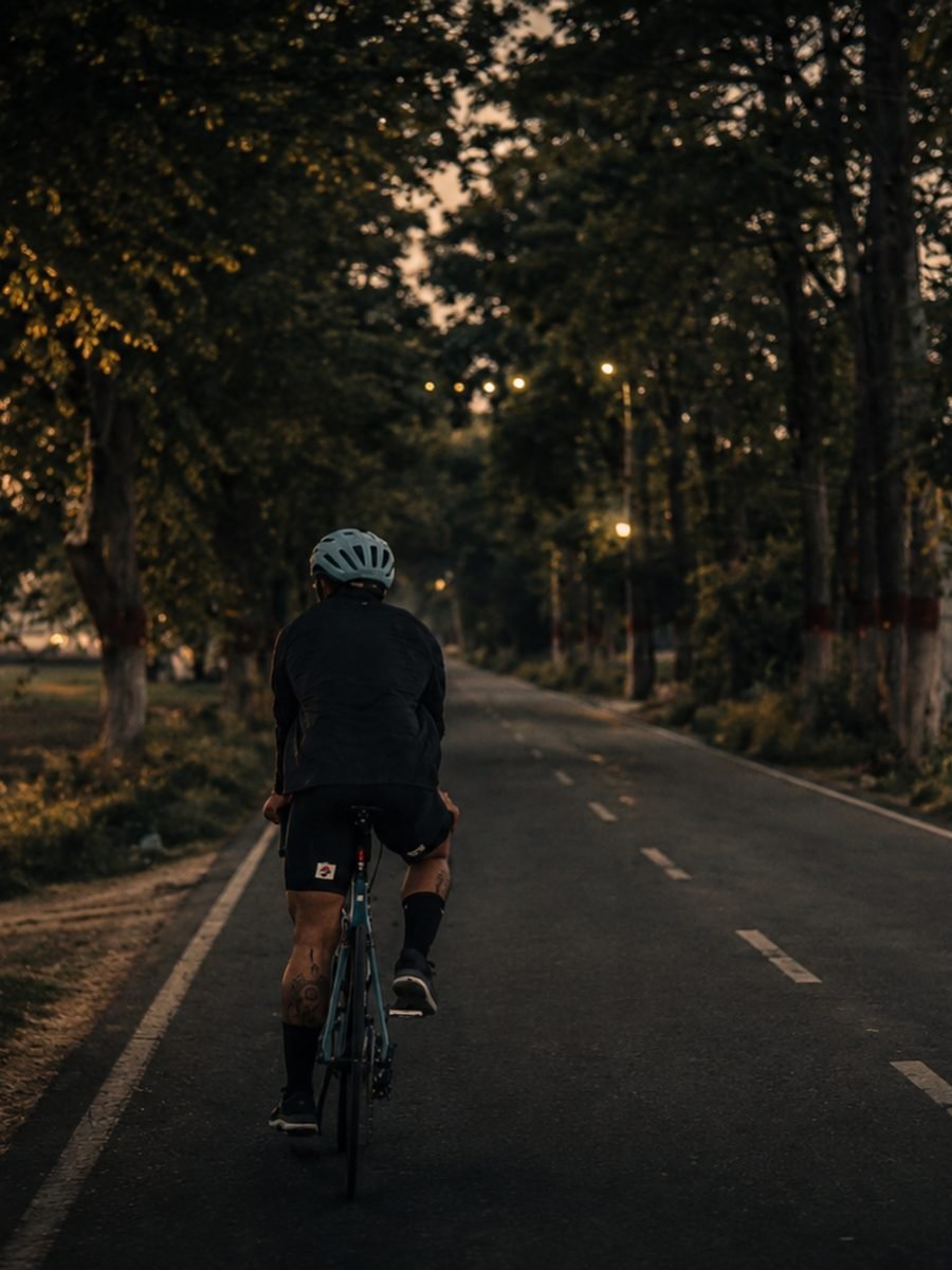 Satnaam riding a road bike down a tree-lined road at dusk